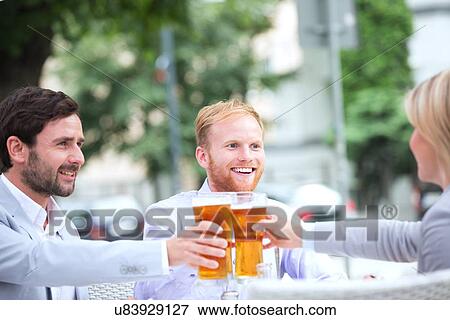 Happy businesspeople toasting beer glasses at outdoor restaurant View Large Photo Image Stock Photo - Happy businesspeople toasting beer glasses at outdoor restaurant. Fotosearch