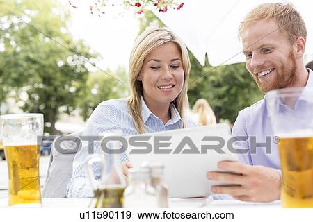 Happy businesspeople using digital tablet at sidewalk cafe View Large Photo Image Stock Photo - Happy businesspeople using digital tablet at sidewalk cafe. Fotosearch