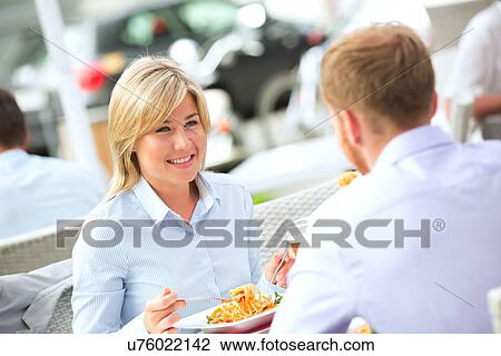 Happy businesswoman having food with male colleague at outdoor restaurant View Large Photo Image Stock Image - Happy businesswoman having food with male colleague at outdoor restaurant. Fotosearch