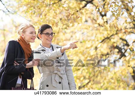 Happy businesswoman showing something to colleague at park View Large Photo Image Stock Photograph - Happy businesswoman showing something to colleague at park. Fotosearch