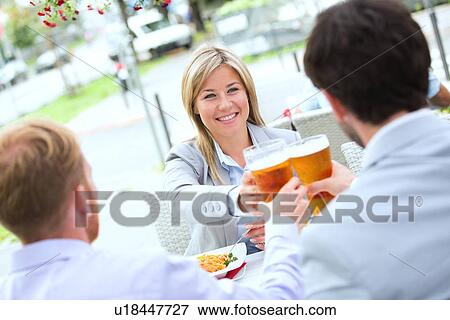 Happy businesswoman toasting beer glass with male colleagues at sidewalk cafe View Large Photo Image Stock Photo - Happy businesswoman toasting beer glass with male colleagues at sidewalk cafe. Fotosearch