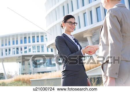 Happy businesswomen shaking hands outside office building View Large Photo Image Picture - Happy businesswomen shaking hands outside office building. Fotosearch