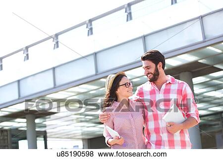 Stock Photo - Happy couple looking at each other while walking in city. Fotosearch