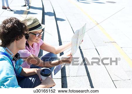 Happy couple reading map while sitting on steps outdoors View Large Photo Image Stock Image - Happy couple reading map while sitting on steps outdoors. Fotosearch