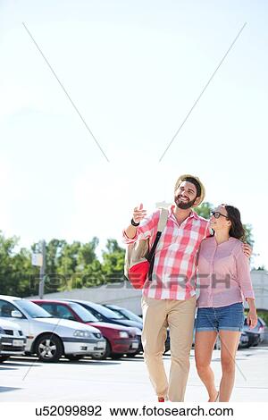 Happy couple walking on city street against clear sky View Large Photo Image Stock Image - Happy couple walking on city street against clear sky. Fotosearch