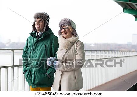 Stock Photo - Happy couple walking on footpath during winter. Fotosearch