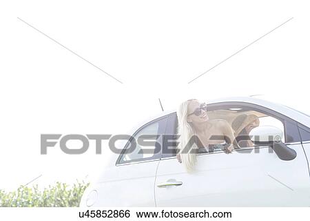 Happy female friends enjoying in car against clear sky View Large Photo Image Stock Photograph - Happy female friends enjoying in car against clear sky. Fotosearch