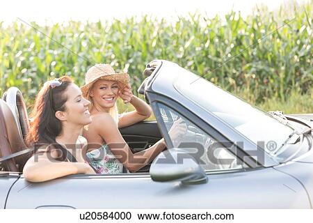 Happy female friends enjoying road trip in convertible View Large Photo Image Stock Image - Happy female friends enjoying road trip in convertible. Fotosearch