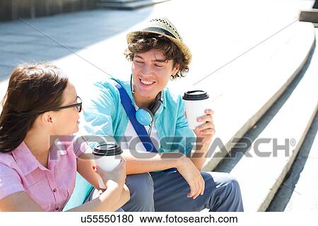 Happy friends holding disposable coffee cups while sitting on steps outdoors View Large Photo Image Stock Image - Happy friends holding disposable coffee cups while sitting on steps outdoors. Fotosearch