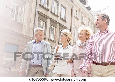 Stock Image - Happy friends talking while walking in city. Fotosearch
