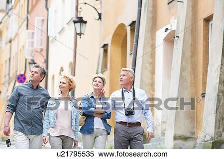 Stock Photography - Happy friends talking while walking in city. Fotosearch
