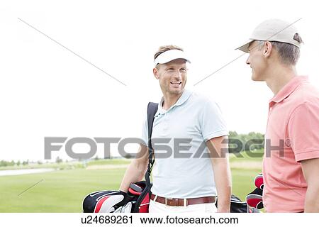 Happy golfer communicating with male friend against clear sky View Large Photo Image Stock Image - Happy golfer communicating with male friend against clear sky. Fotosearch