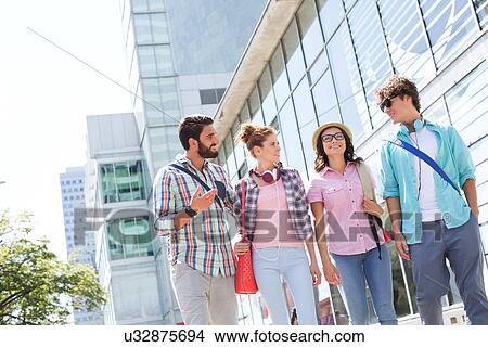 Happy male and female friends walking outside office building View Large Photo Image Picture - Happy male and female friends walking outside office building. Fotosearch