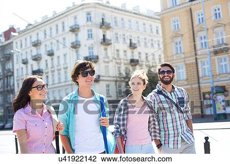 Happy male and female friends walking on city street View Large Photo Image Stock Image - Happy male and female friends walking on city street. Fotosearch