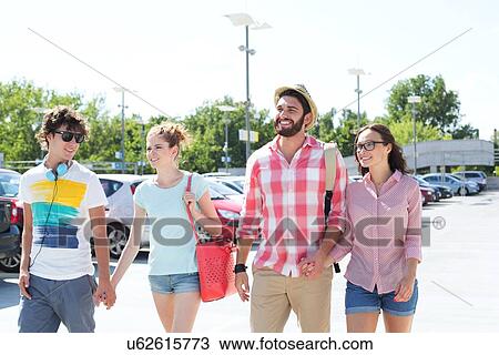 Stock Image - Happy male and female friends walking on city street. Fotosearch