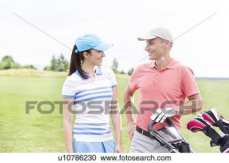 Happy male and female golfers communicating against clear sky View Large Photo Image Stock Image - Happy male and female golfers communicating against clear sky. Fotosearch