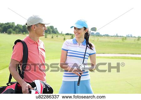 Happy male and female golfers communicating at course View Large Photo Image Stock Photo - Happy male and female golfers communicating at course. Fotosearch