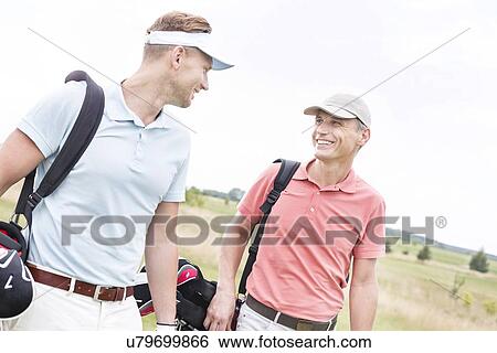 Happy male golfers conversing against clear sky View Large Photo Image Stock Photograph - Happy male golfers conversing against clear sky. Fotosearch