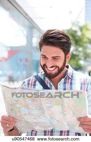 Happy man reading road map in city View Large Photo Image Stock Photo - Happy man reading road map in city. Fotosearch