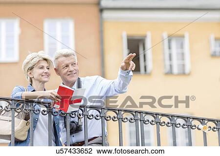Happy man showing something to woman with guidebook in city View Large Photo Image Stock Image - Happy man showing something to woman with guidebook in city. Fotosearch