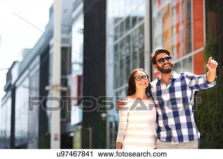 Happy man showing something to woman outside building View Large Photo Image Stock Image - Happy man showing something to woman outside building. Fotosearch