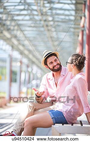 Happy man talking to woman while sitting on bench under shade View Large Photo Image Picture - Happy man talking to woman while sitting on bench under shade. Fotosearch