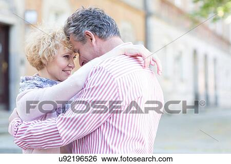 Stock Photograph - Happy middle-aged couple embracing in city. Fotosearch