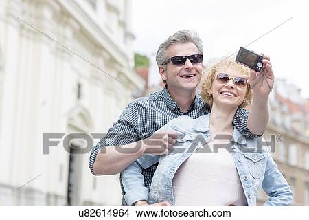Happy middle-aged couple in sunglasses taking self portrait outdoors View Large Photo Image Picture - Happy middle-aged couple in sunglasses taking self portrait outdoors. Fotosearch