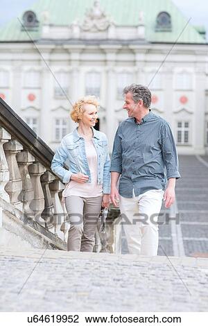 Happy middle-aged couple looking at each other while climbing steps View Large Photo Image Stock Image - Happy middle-aged couple looking at each other while climbing steps. Fotosearch