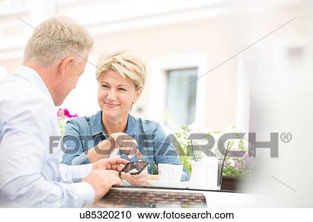 Happy middle-aged couple using cell phone at sidewalk cafe View Large Photo Image Stock Image - Happy middle-aged couple using cell phone at sidewalk cafe. Fotosearch