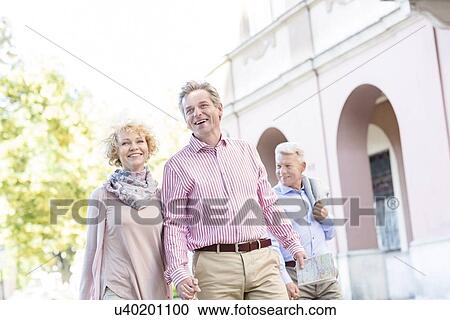 Happy middle-aged couple with map walking in city View Large Photo Image Stock Image - Happy middle-aged couple with map walking in city. Fotosearch