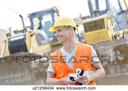 Happy supervisor looking away at construction site View Large Photo Image Picture - Happy supervisor looking away at construction site. Fotosearch