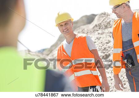 Stock Photo - Happy supervisor with colleague at construction site. Fotosearch