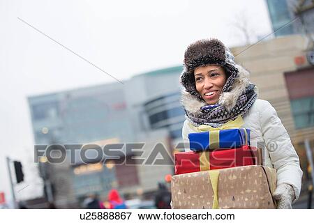 Happy woman looking away while carrying stacked gifts during winter View Large Photo Image Stock Photo - Happy woman looking away while carrying stacked gifts during winter. Fotosearch
