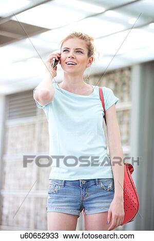 Happy woman looking away while using cell phone outdoors View Large Photo Image Stock Image - Happy woman looking away while using cell phone outdoors. Fotosearch