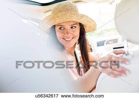 Happy woman looking back while driving car View Large Photo Image Stock Photo - Happy woman looking back while driving car. Fotosearch