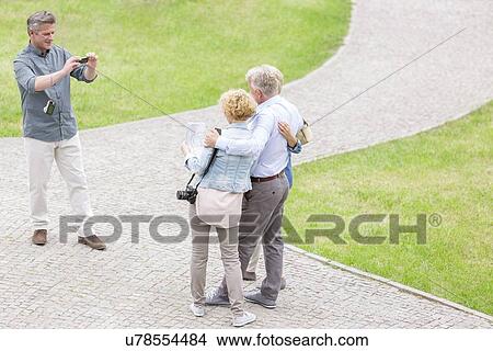 Picture - High angle view of man photographing friends at park. Fotosearch