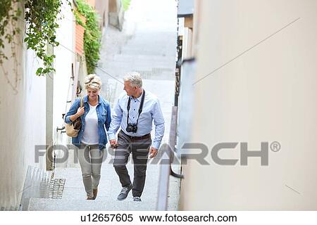 Stock Photography - High angle view of middle-aged couple holding hands while climbing steps outdoors. Fotosearch