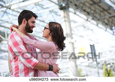 Stock Image - Loving couple looking at each other while embracing outside building. Fotosearch