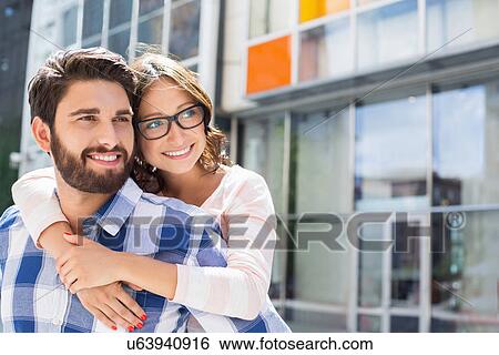 Loving man piggybacking woman in city View Large Photo Image Stock Photograph - Loving man piggybacking woman in city. Fotosearch
