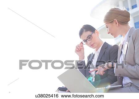 Low angle view of businesswomen using laptop against clear sky View Large Photo Image Stock Photograph - Low angle view of businesswomen using laptop against clear sky. Fotosearch