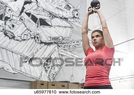 Low angle view of dedicated woman lifting kettlebell in crossfit gym View Large Photo Image Stock Image - Low angle view of dedicated woman lifting kettlebell in crossfit gym. Fotosearch