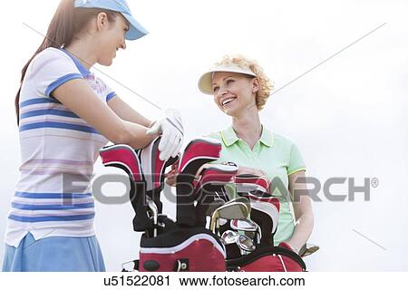 Low angle view of happy female golfers talking against clear sky View Large Photo Image Stock Image - Low angle view of happy female golfers talking against clear sky. Fotosearch