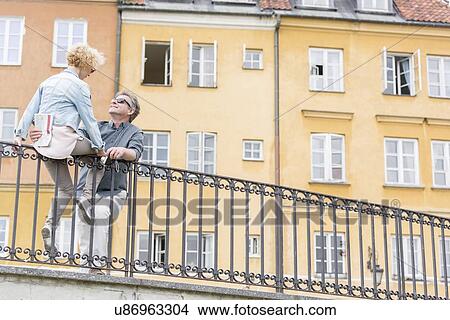Low angle view of loving middle-aged couple by railing against building View Large Photo Image Picture - Low angle view of loving middle-aged couple by railing against building. Fotosearch