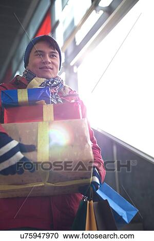 Low angle view of man holding gifts by window View Large Photo Image Stock Image - Low angle view of man holding gifts by window. Fotosearch