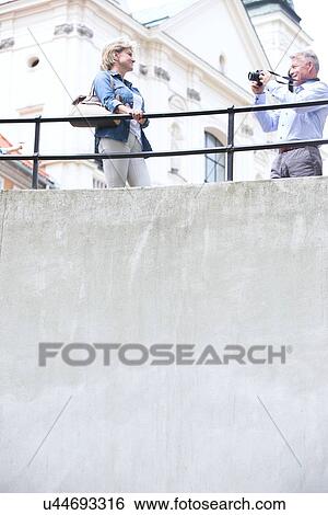 Low angle view of man photographing woman by railing outside church View Large Photo Image Stock Photograph - Low angle view of man photographing woman by railing outside church. Fotosearch