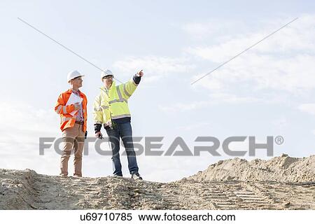 Low angle view of supervisor showing something to colleague at construction site View Large Photo Image Stock Photography - Low angle view of supervisor showing something to colleague at construction site. Fotosearch