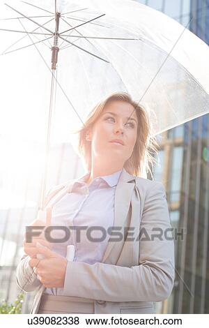 Low angle view of thoughtful businesswoman holding umbrella outdoors View Large Photo Image Stock Photo - Low angle view of thoughtful businesswoman holding umbrella outdoors. Fotosearch