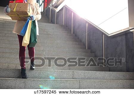 Low angle view of woman with gifts and shopping bags moving down steps View Large Photo Image Stock Photography - Low angle view of woman with gifts and shopping bags moving down steps. Fotosearch