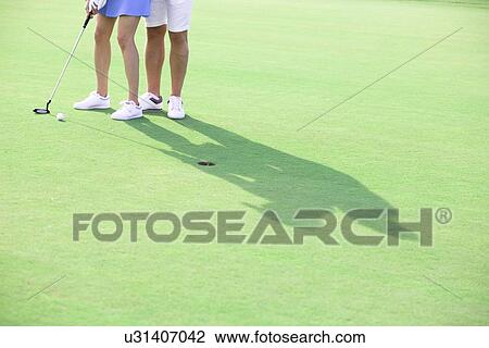Low section of couple playing golf at course View Large Photo Image Stock Image - Low section of couple playing golf at course. Fotosearch